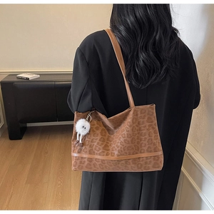 Détail du sac cabas léopard avec lanières en cuir marron et breloque pelucheuse