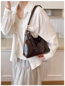 Detail of glossy chocolate brown hobo bag with unique pretzel charm and fashion logo