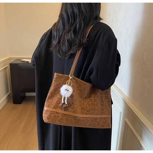 Détail du sac cabas léopard avec texture en daim et pendentif monstre en peluche blanc doux