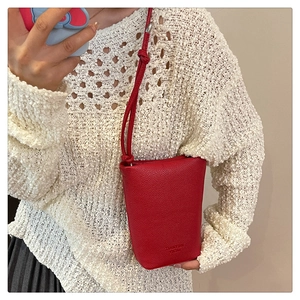 Detail der roten Eimertasche mit Lychee-Struktur und Knotengurt am Modell