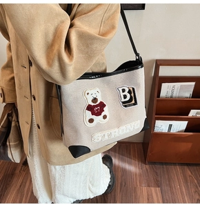 Dettaglio della borsa tote in tela con ricamo a forma di orso e bordi in pelle nera