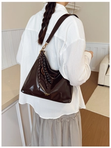 Detail of dark brown glossy shoulder bag with silk scarf and gold fashion text