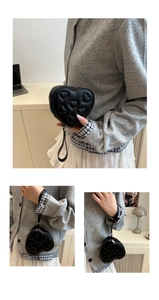 Detail of black heart-shaped PU mini bag with quilted embroidery and wrist strap