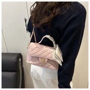 Detailed shot of pink quilted crossbody bag featuring silk scarf handle and gold twist lock