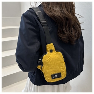 Close-up of bright yellow nylon crossbody bag worn over shoulder in casual style