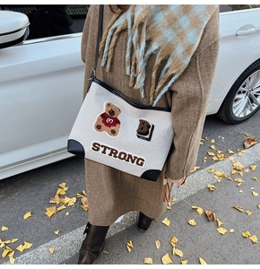 Primo piano del ricamo dell'orso e delle scritte sulla borsa tote in tela con bordi in pelle
