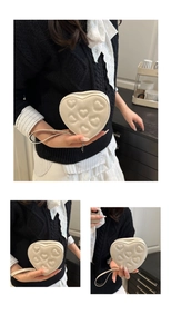 Macro shot of cream heart-shaped PU purse with quilted embroidery and wrist strap