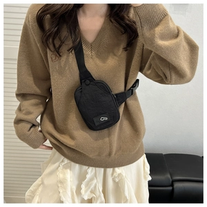 Detail of waterproof nylon crossbody bag shown worn by a model in a casual outfit