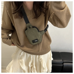 Detail of olive green nylon crossbody bag showing the fabric texture and buckle strap