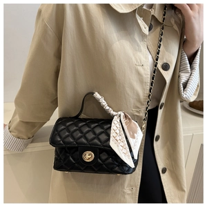 Quilted black crossbody bag with gold lock and silk scarf detail on handle shown on model