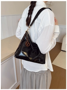 Detail of black glossy tote bag with woven rope trim and golden lettering on shoulder strap