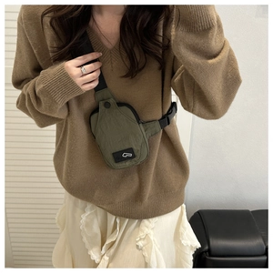 Detail of army green nylon crossbody chest bag with adjustable strap worn by model