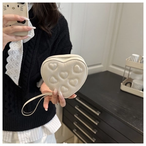 Dettaglio macro della mini borsa crema a cuore con ricamo a cuore trapuntato in 3D