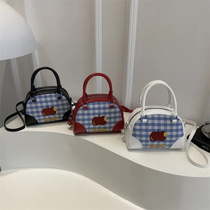 Blue plaid bowling handbag with apple graphic and crossbody strap on modern white display