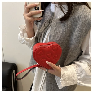 Detail van rode hartvormige crossbodytas met gewatteerd borduursel en zilveren rits