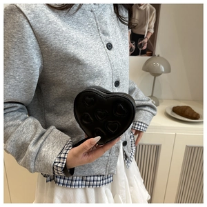 Detailed view of black heart-shaped quilted mini bag with premium leather texture