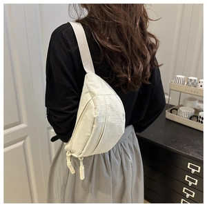 Detail of off-white corduroy chest bag featuring vertical texture and double zip closure