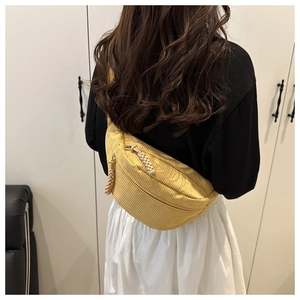 Detail of yellow corduroy crossbody bag featuring dual zippers with woven pullers