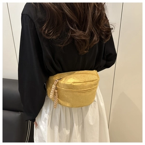 Detail view of a bright yellow corduroy waist bag worn on a casual monochrome outfit