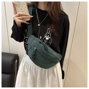 Detail of dark green corduroy crossbody bag texture and woven zipper on model