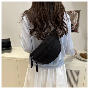 Close-up of black corduroy moon-shaped crossbody chest bag with woven zipper details