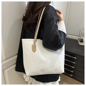 Detail view of woven textured white tote bag with beige shoulder strap for daily use