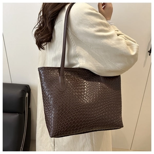 Detail of dark brown woven tote bag with Intrecciato texture and long shoulder strap