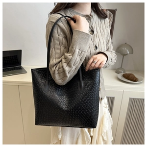 Detailed close-up showing texture of the black woven leather tote bag with shoulder straps