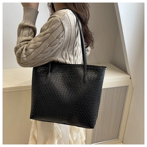 Detail of black woven texture large tote bag shown on model with cozy knit sweater