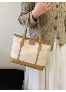Detail view of canvas and leather tote bag worn by model in minimalist knit sweater