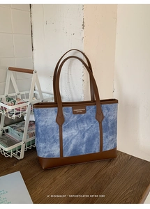 Close-up of denim blue tote bag showing clear fabric texture and brown leather trim