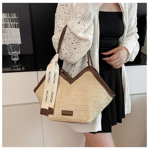 Close-up of woven straw tote bag with brown leather trim and decorative silk scarf
