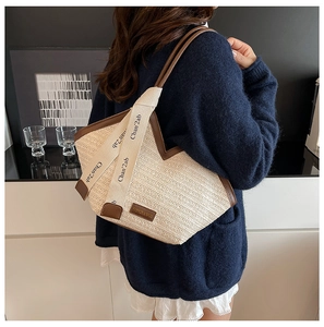 Detail of beige woven tote bag with brown leather trim and printed wide fabric shoulder strap