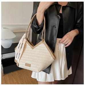 Detail of contrast stitch straw tote bag featuring a decorative scarf on the handle
