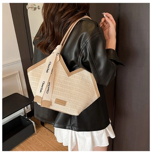 Detail of beige woven tote bag with V-shaped opening and lettered shoulder strap