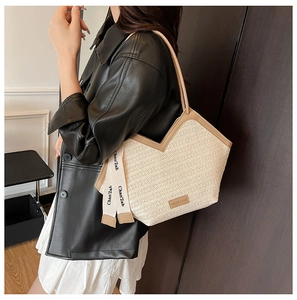 Close-up of contrast woven tote with leather trim and decorative ribbon detail