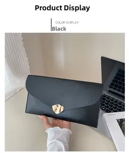 Détail d'une grande pochette enveloppe en similicuir noir avec boucle en métal doré