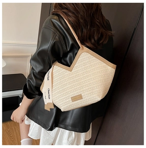 Detail of a beige woven tote bag with V-shaped cut and contrasting leather shoulder straps