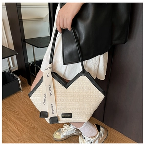 Detail of contrast beige woven tote bag with black leather handles and silk scarf