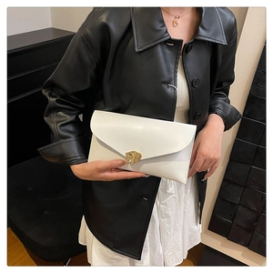 Détail de la pochette enveloppe blanche avec fermoir doré sur cuir mat élégant