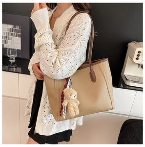 Detail of large beige tote bag with litchi texture and brown straps on a model