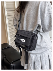 Detailed view of the black nylon messenger bag with adjustable strap and logo patch