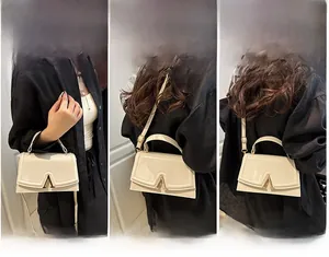 Detail view of cream small square bag showing handheld, shoulder and crossbody carrying ways
