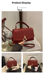 Detail of red leather bag with gold V-buckle showing texture and shoulder strap