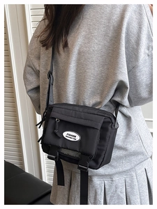 Detail of black nylon crossbody bag with adjustable strap and multiple zipper pockets