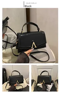Detailed shot of black patent leather handbag featuring a golden V-shaped metal buckle