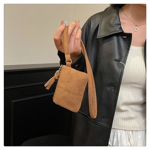 Detailed view of the tan suede mini bag featuring a stylish tassel zipper and long handle
