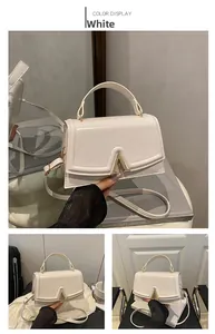 Detail of white glossy patent leather handbag with V-shaped gold metal clasp