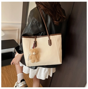 Lifestyle view of a large beige JK uniform tote bag with brown straps and bear charm