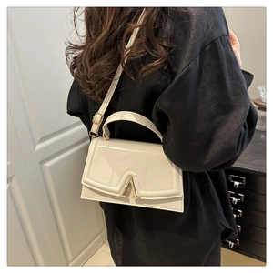 Side view of a creamy white leather handbag featuring a distinct gold A-shaped metal clasp